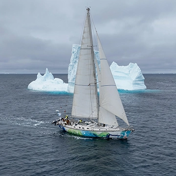Un yate navega junto a un iceberg